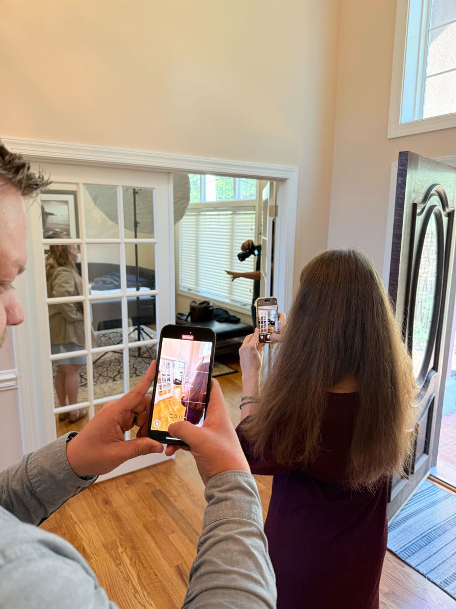 Letterpress team members document a photoshoot on their cell phones. A smartphone camera view is visible, demonstrating the photography rule of thirds. The photographer is positioning the subject in the right third of the image.
